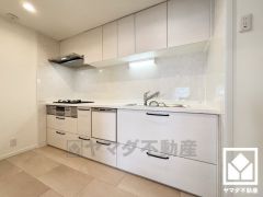 キッチンは空間を有効活用できる壁付けタイプ。白色で統一された明るく清潔感のあるデザインが魅力のシステムキッチンです。