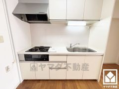 キッチンは空間を有効活用できる壁付けタイプ。明るい白色で統一された清潔感のあるデザインが魅力のシステムキッチンです。