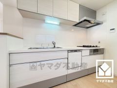 キッチンは空間を有効活用できる壁付けタイプ。明るい白色を基調とした清潔感のあるデザインが魅力のシステムキッチンです。