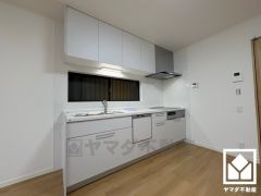 キッチンは空間を有効活用できる壁付けタイプ。明るい白色で統一された清潔感のあるデザインが魅力のシステムキッチンです。