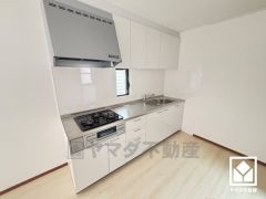 キッチンは空間を有効活用できる壁付けタイプ。換気効率が高いブーツ型のレンジフードを完備。調理に手間がかかりがちな肉や魚を、短時間でサッと焼き上げることができるグリル付き。