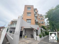 畑田建築計画所設計、陽光に映える美しい外観のデザイナーズマンション。街並みに馴染みながらも、ひときわ目を引く存在感。