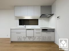 キッチンは空間を有効活用できる壁付けタイプ。明るい白色で統一された清潔感のあるデザインが魅力のシステムキッチンです。