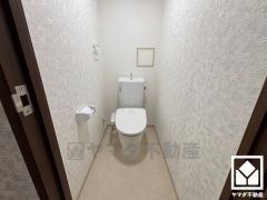 明るく清潔感溢れるトイレです。タオル掛けやペーパーホルダーが設置されています。