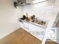 キッチンは空間を有効活用できる壁付けタイプ。明るい白色で統一された清潔感のあるデザインが魅力のシステムキッチンです。