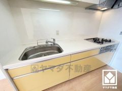 キッチンは空間を有効活用できる壁付けタイプ。背面にはカウンター付きのキャビネットがございますので配膳や片付けがしやすくなり、スッキリとした空間が保てます。