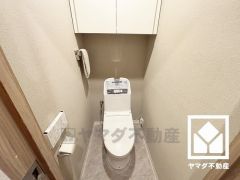 明るく清潔感溢れるトイレです。トイレットペーパーのストックや消耗品置き場などとしてお使いいただける吊戸棚がございます。